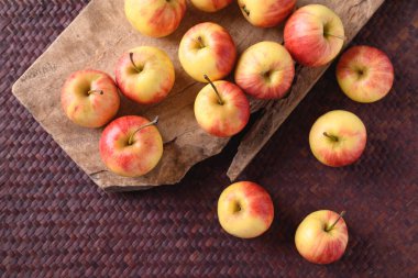 Ahşap ve kırmızı zemin üzerinde taze kırmızı elma meyvesi, masa üstü görünümü