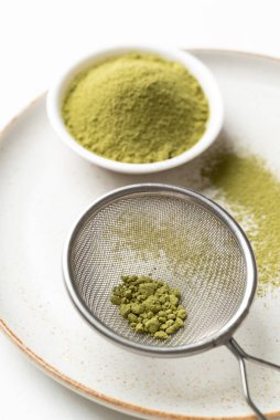 Matcha green tea powder in sieve on plate prepare for tea mixing