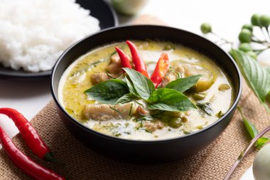 Tayland yeşil köri tavuğu, siyah kâse içinde pirinç ve malzemelerle.