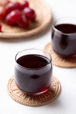 Bardakta kırmızı üzüm suyu ve beyaz arka planda taze üzüm meyvesi, sağlıklı içecek.