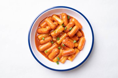 Tteokbokki (haşlanmış pirinç keki) ve beyaz arka planda baharatlı soslu sosis, Kore yemeği.