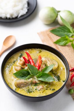 Tayland yeşil körili tavuğu siyah kasede pilav ve malzemeler beyaz arka planda.