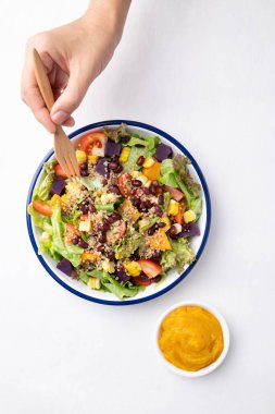 Marullu sağlıklı sebze salatası, kinoa tohumu, azuki fasulyesi, mısır, domates, balkabağı ve mor patatesli kabak kabağı soslu beyaz arka planda. Vejetaryen ve bitkisel gıda