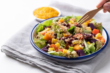 Marullu sağlıklı sebze salatası, kinoa tohumu, azuki fasulyesi, mısır, domates, balkabağı ve mor patatesli kabak kabağı soslu beyaz arka planda. Vejetaryen ve bitkisel gıda