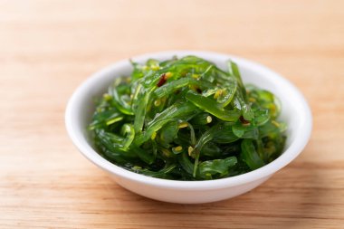 Tahta arka planda susam tohumlu yosun salatası.