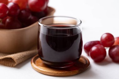 Bardakta kırmızı üzüm suyu ve beyaz arka planda taze üzüm meyvesi, sağlıklı içecek.