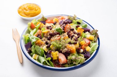 Marullu sağlıklı sebze salatası, kinoa tohumu, azuki fasulyesi, mısır, domates, kabak kabağı ve mor tatlı patates ve beyaz arka planda kabak sosu. Vejetaryen ve bitkisel gıda