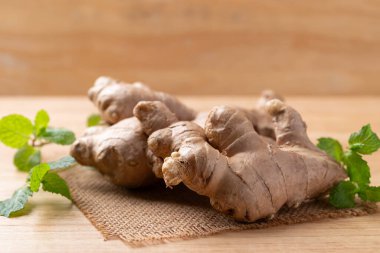 Tahta zemin üzerinde nane yaprağı olan taze zencefil.