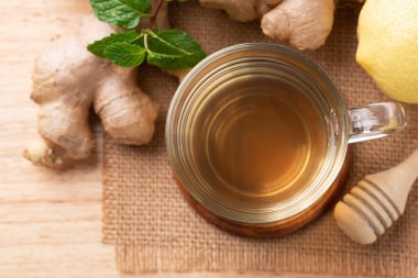 Ahşap zemin üzerinde bardakta limon ve zencefil çayı, sağlıklı sıcak içecek.