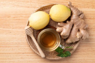 Ahşap zemin üzerinde bardakta limon ve zencefil çayı, sağlıklı sıcak içecek.