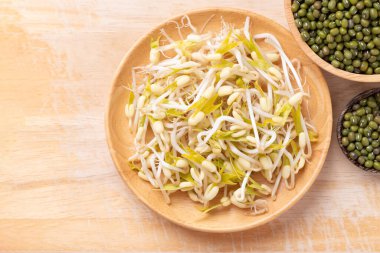 Ahşap arka planda Mung fasulyesi filizleri ve tohumlar, Asya mutfağında gıda malzemeleri.