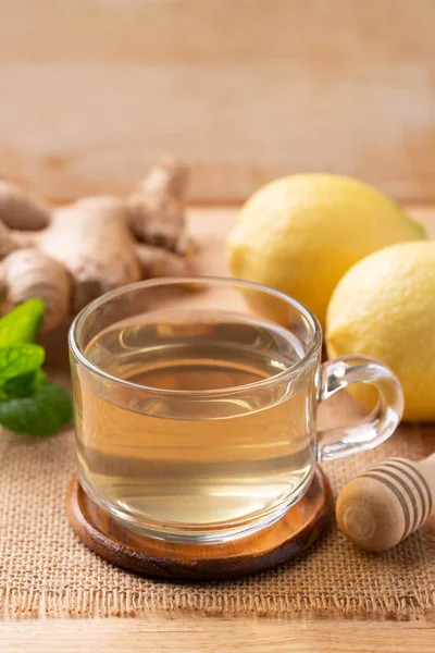 Ahşap zemin üzerinde bardakta limon ve zencefil çayı, sağlıklı sıcak içecek.