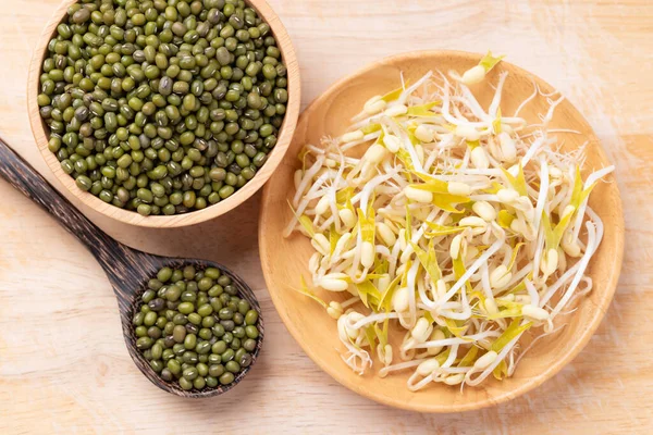 Ahşap arka planda Mung fasulyesi filizleri ve tohumlar, Asya mutfağında gıda malzemeleri.