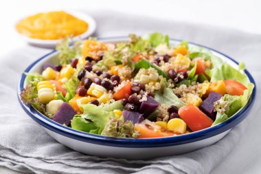 Marullu sağlıklı sebze salatası, kinoa tohumu, azuki fasulyesi, mısır, domates, balkabağı ve kabak kabağı soslu mor tatlı patates. Vejetaryen ve bitkisel gıda