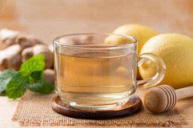 Ahşap zemin üzerinde bardakta limon ve zencefil çayı, sağlıklı sıcak içecek.