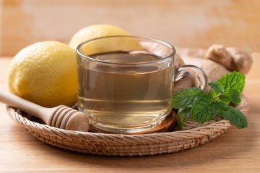 Ahşap zemin üzerinde bardakta limon ve zencefil çayı, sağlıklı sıcak içecek.