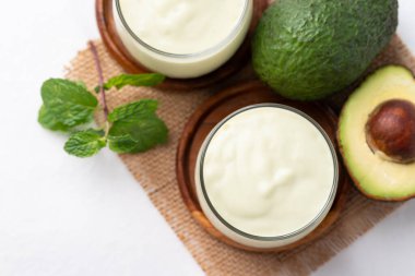 Bardakta süt ve beyaz arka planda avokado meyveli avokado smoothie, sağlıklı içecek.