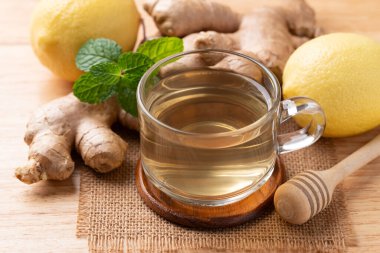 Ahşap zemin üzerinde bardakta limon ve zencefil çayı, sağlıklı sıcak içecek.