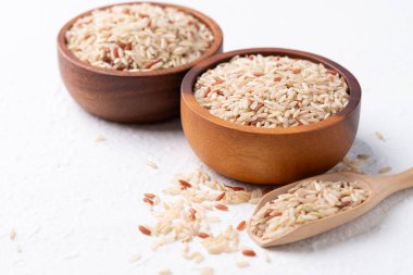 Tahta kase içinde Tayland kahverengi pirinç tohumu (İskoç yabani pirinci) ve beyaz arka planda kepçe