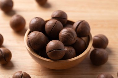 Ahşap arka planda kabukta soyulmamış Macadamia fındıkları