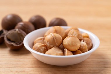 Ahşap arka planda kabukta soyulmuş macadamia fındıkları.