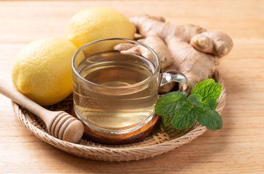 Ahşap zemin üzerinde bardakta limon ve zencefil çayı, sağlıklı sıcak içecek.