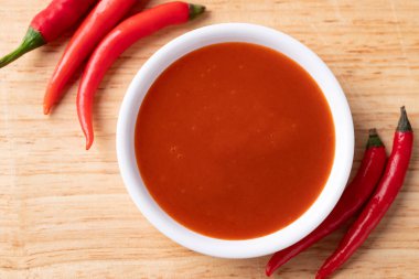 Ahşap arka planda bir kasede Sriracha sosu, Chili sosu, masa üstü manzarası.