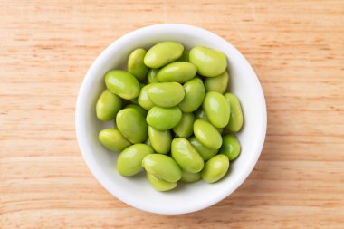 Boiled Edamame beans (Japanese soybeans) in a bowl on wooden background, Table top view