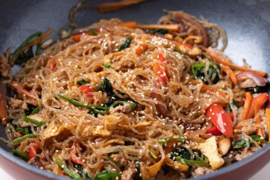 Japchae, Korean stir fried glass noodles with vegetables, pork, soy sauce and sesame oil in cooking pan
