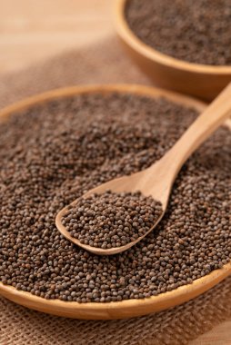 Kahverengi arka planda kaşık ve kâsede kurutulmuş perilla tohumu.