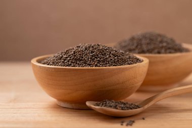 Tahta zemin üzerinde kaşık olan bir kasede kurutulmuş perilla tohumu.