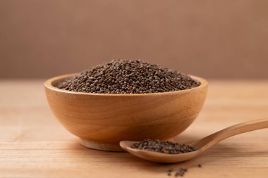 Tahta zemin üzerinde kaşık olan bir kasede kurutulmuş perilla tohumu.