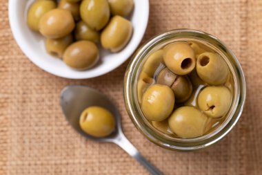 Turşulu zeytin, cam kavanozda çukur yeşil zeytin ve kaşık.