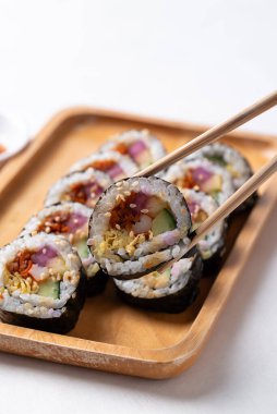 Kimbap ya da Gimbap, sebzeli pilav, yumurta ve ahşap tabakta kurutulmuş yosunla sarılı Kore yemeği.