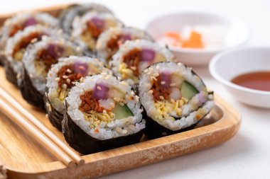 Kimbap veya Gimbap, sebzeli pilav, yumurta ve ahşap tabakta kurutulmuş yosunla sarılmış Kore yemeği.