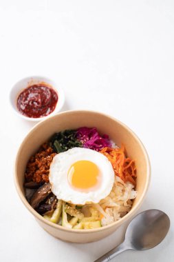 Bibimbap, Kore yemeği, sebzeli pilav, biyolojik çözünür kasede domuz ve yumurta ve beyaz arka planda gochujang.