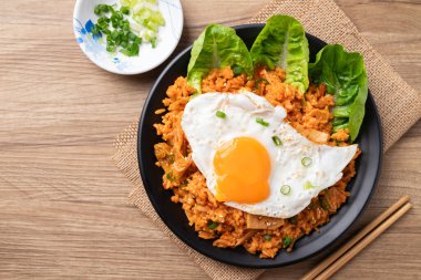 Kore kimchi pilavı, kızarmış yumurta ve taze soğan, masa üstü manzaralı.
