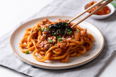 Kızarmış Udon şehriyesini lahana, domuz eti, taze soğan, susam tohumu ve deniz yosunuyla karıştır.