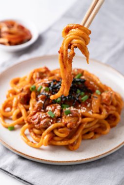 Kızarmış Udon şehriyesini kimchi, lahana, domuz, taze soğan, susam tohumu ve çubuklarla yenen yosunla karıştır.