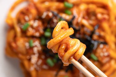 Kızarmış Udon şehriyesini kimchi, lahana, domuz, taze soğan, susam tohumu ve çubuklarla yenen yosunla karıştır.
