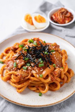 Kızarmış Udon şehriyesini lahana, domuz eti, taze soğan, susam tohumu ve deniz yosunuyla karıştır.