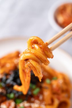 Kızarmış Udon şehriyesini kimchi, lahana, domuz, taze soğan, susam tohumu ve çubuklarla yenen yosunla karıştır.