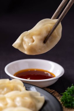 Susam yağı sosuna batırılmış lezzetli buğulanmış hamur köftelerini yakın çekim.