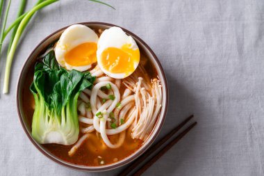 Baharatlı Udon Erişte Çorbası 'nın üst görüntüsü Bok Choy, Enoki Mantarı ve yumuşak kaynamış yumurta karışımı.