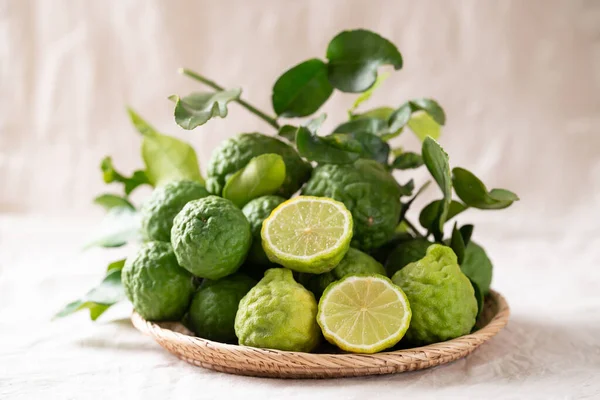 Beyaz kumaş arka planında yaprak olan Kaffir limon meyvesi, Tayland yemeği malzemesi.