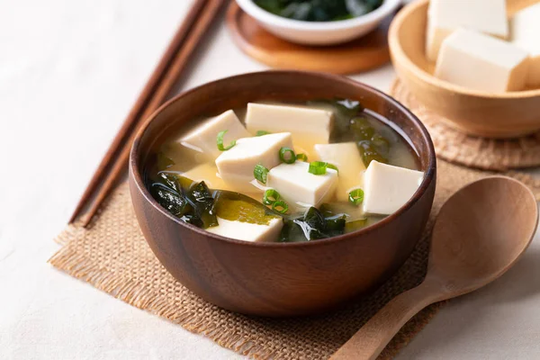 Sağlıklı Japon miso çorbası yumuşak tofu ve ahşap bir kasede yosun, kaşık ve yemek çubuklarıyla servis edilir.