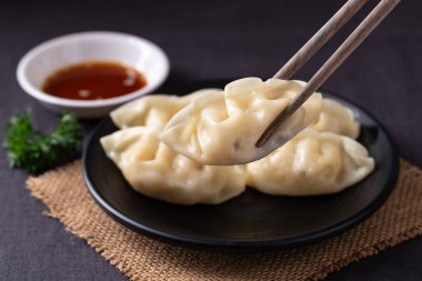 Yemek çubuğu ve susam yağı soslu enfes buharda pişirilmiş hamur köftelerini yakın.