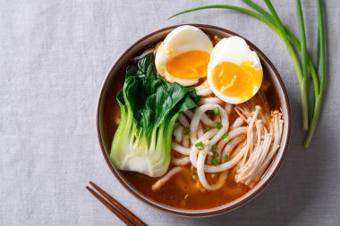 Baharatlı Udon Erişte Çorbası 'nın üst görüntüsü Bok Choy, Enoki Mantarı ve yumuşak kaynamış yumurta karışımı.