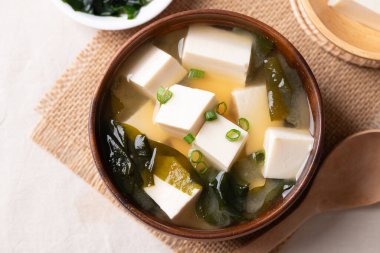 Sağlıklı Japon miso çorbasının üst görüntüsü yumuşak tofu ve yosun ile kaşık ile ahşap bir kasede