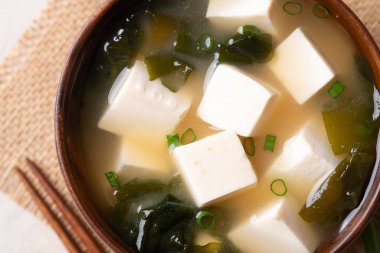 Sağlıklı Japon miso çorbası, yumuşak tofu ve yemek çubuklarıyla ahşap bir kasede yosun.